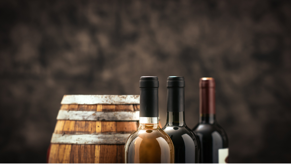 Una botte sullo sfondo e tre vini pregiati in primo piano